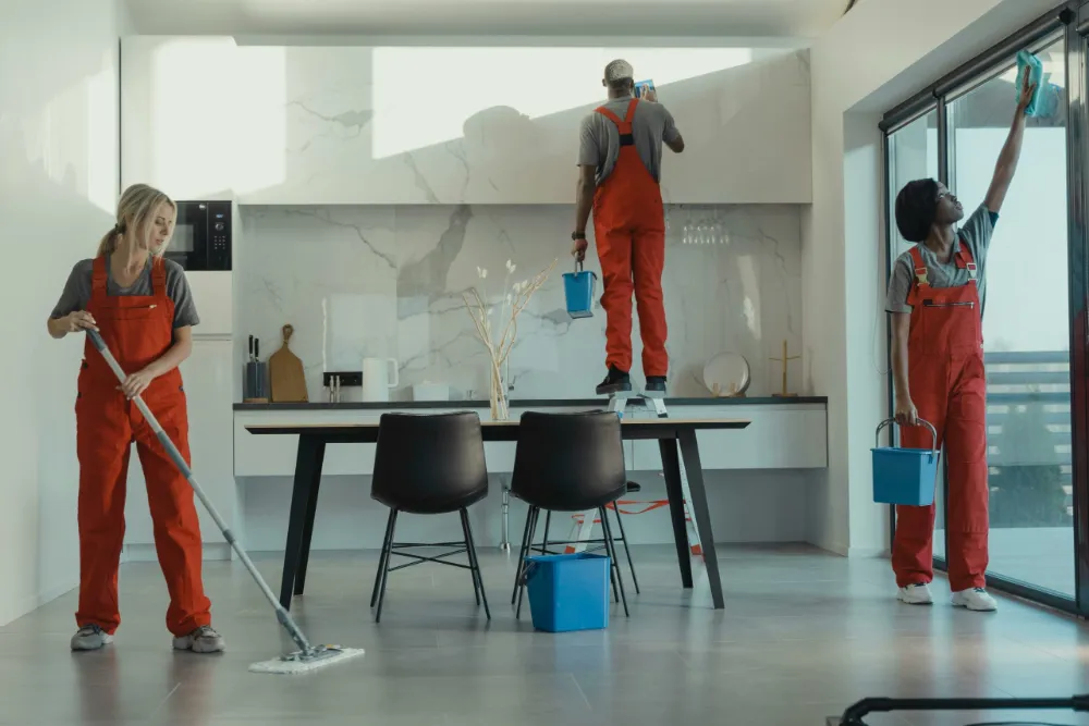 Équipe de ménage nettoyant la cuisine et le séjour d'un appartement