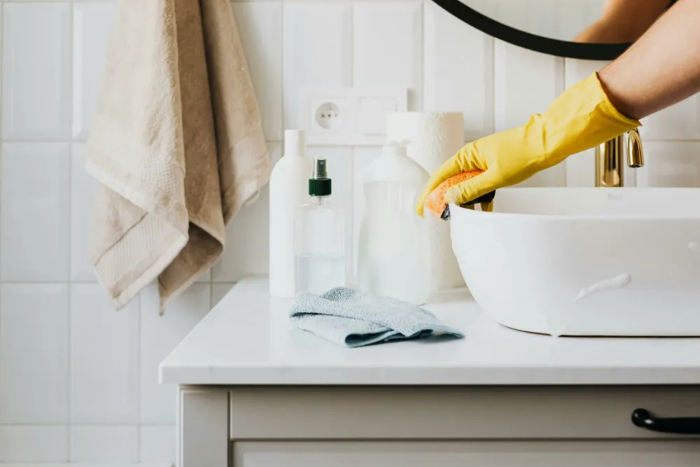 Nettoyage du lavabo et de la salle de bain avec des gants de ménage